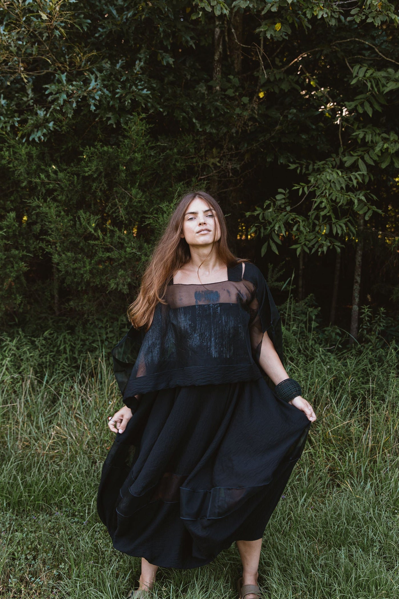 Woman in a black dress standing in a forest